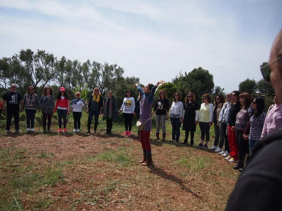 group of tourists holding hands in circle and listening to a woman at holistic workshop at Korogonas Ark outside